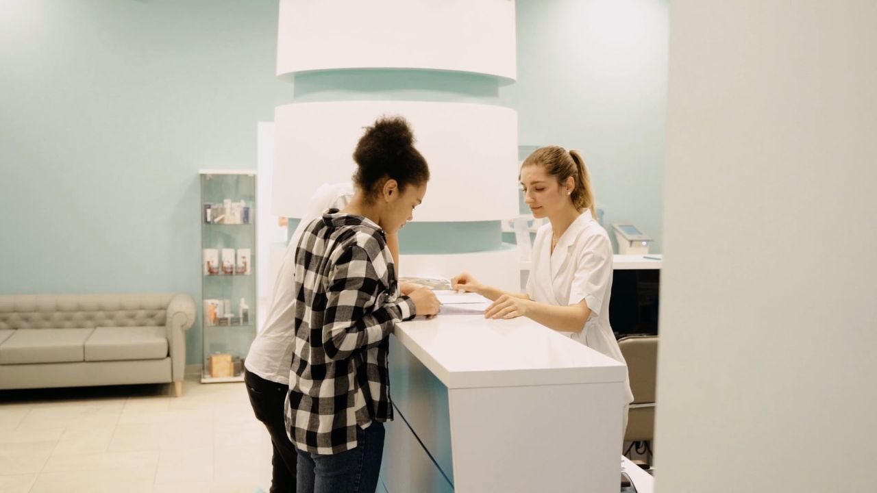 Patientin wird an der Rezeption einer Praxis empfangen